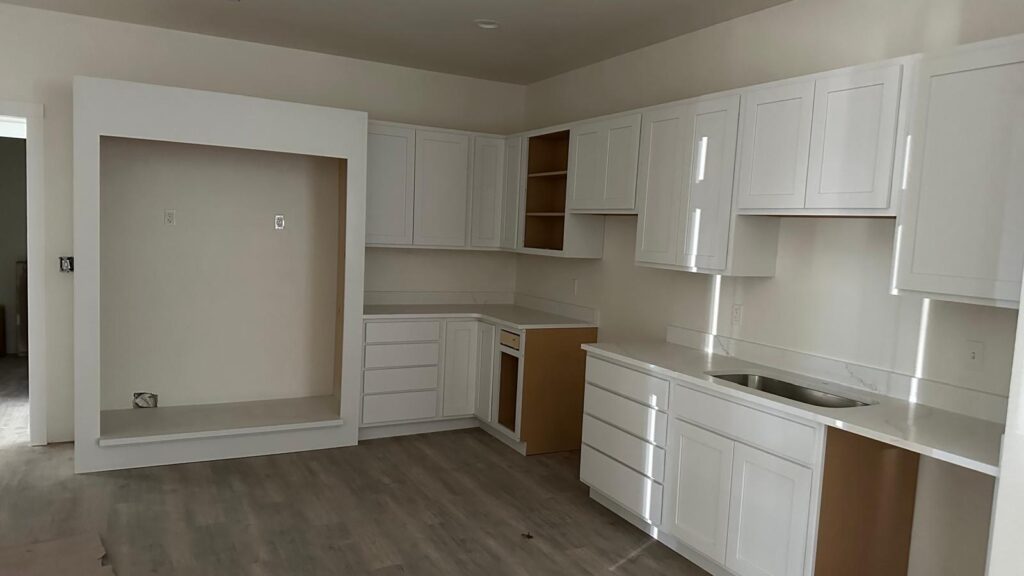 Bespoke white kitchen cabinets featuring custom built-in appliance surround and modern black hardware.