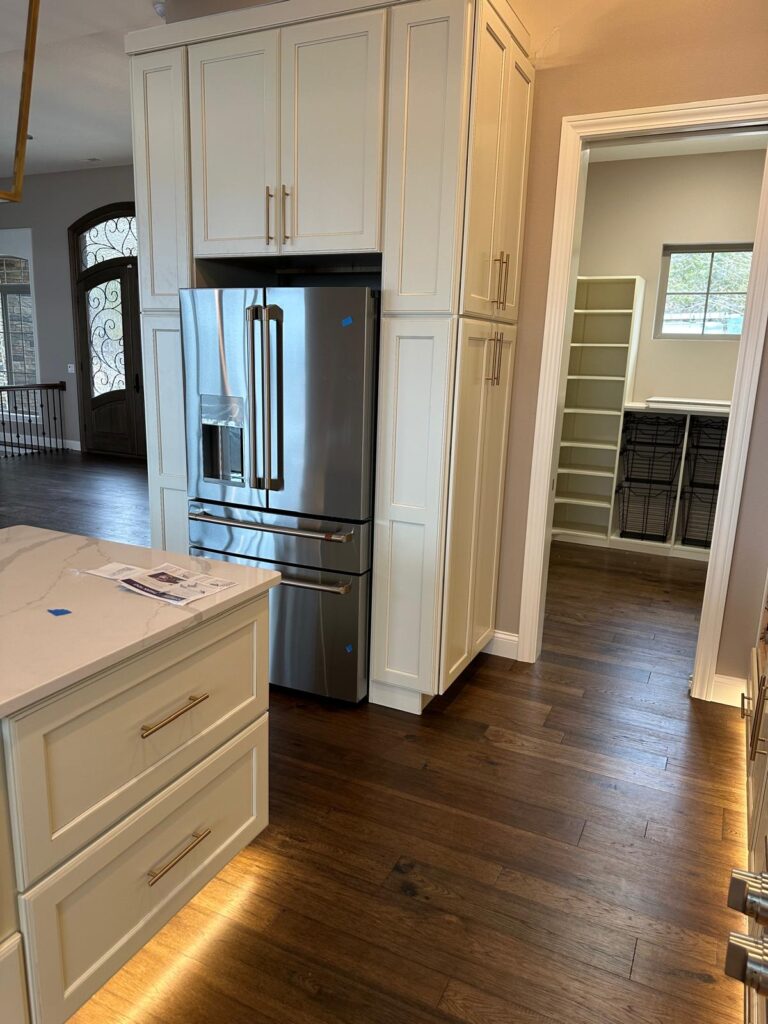 Custom floor-to-ceiling kitchen cabinetry in light gray with integrated refrigerator surround and crown molding.
