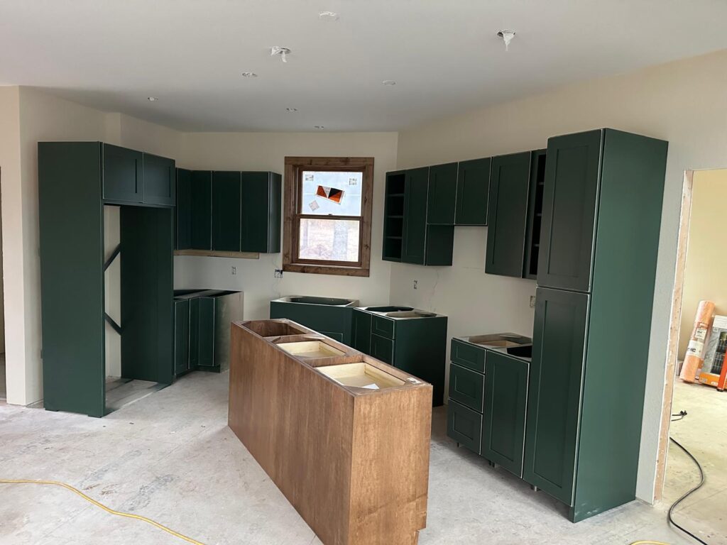 Custom white oak kitchen cabinets with a large marble island, black range hood, and natural stone wall by Max Craft.