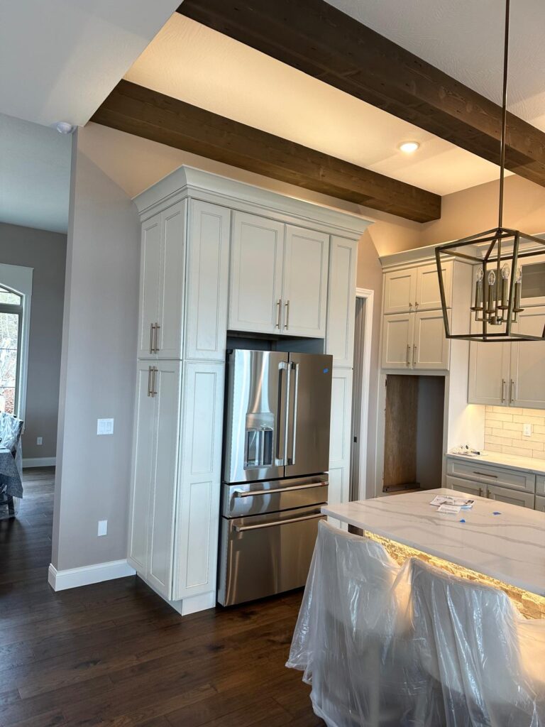 Bespoke high-ceiling kitchen cabinets with stacked storage units and professional-grade appliance integration.