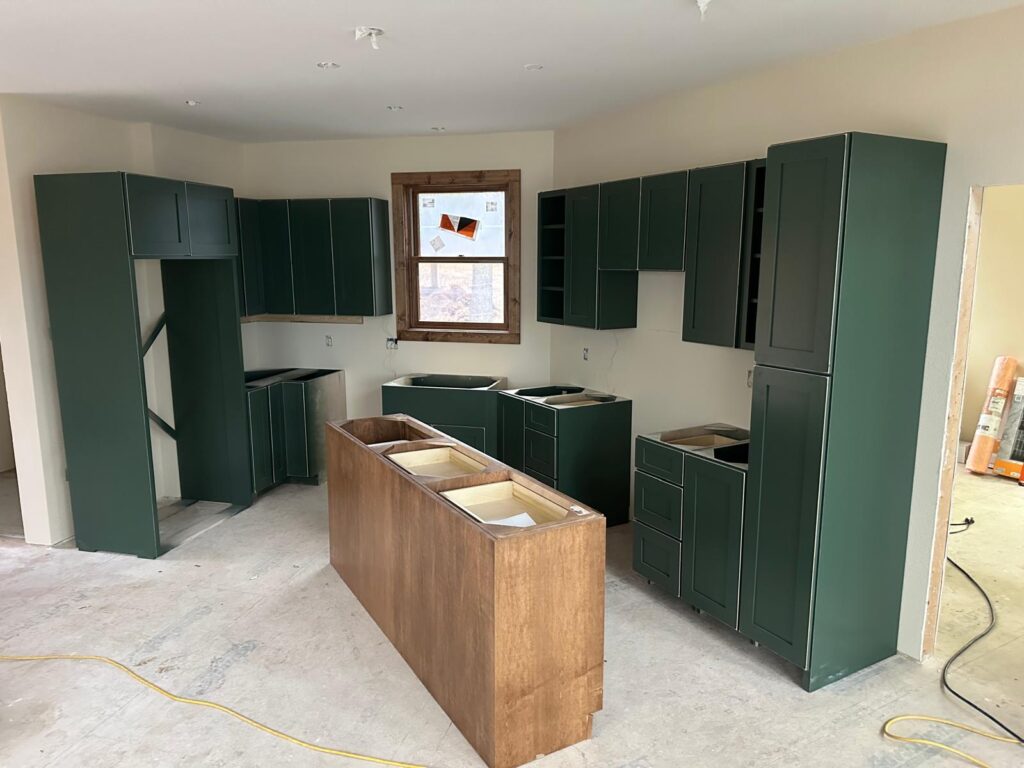 Custom white oak kitchen cabinets with a large marble island, black range hood, and natural stone wall by Max Craft.
