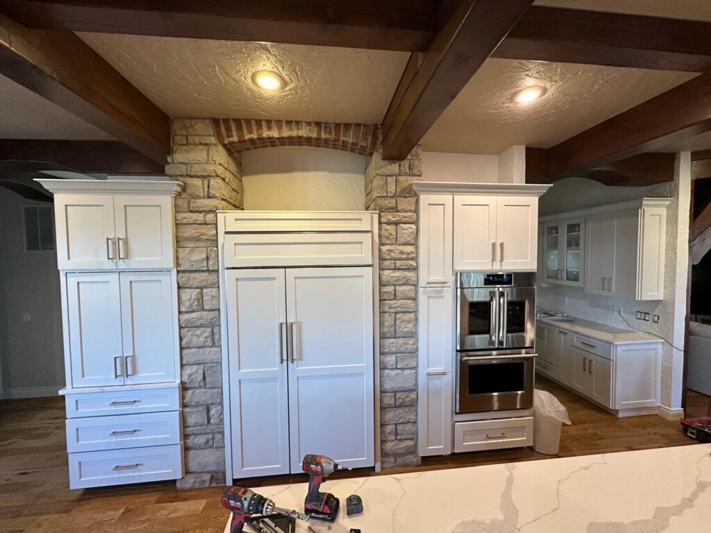 Bespoke appliance wall featuring stacked double ovens and custom cabinetry with handcrafted crown molding