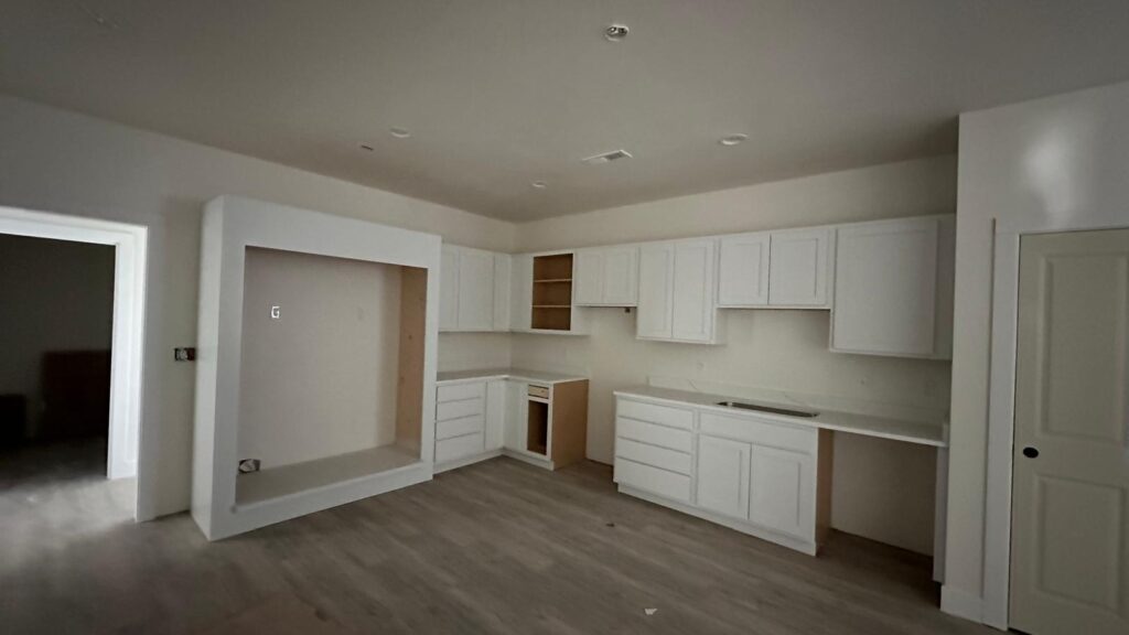 Bespoke white Shaker-style kitchen cabinets with stacked storage and crown molding.