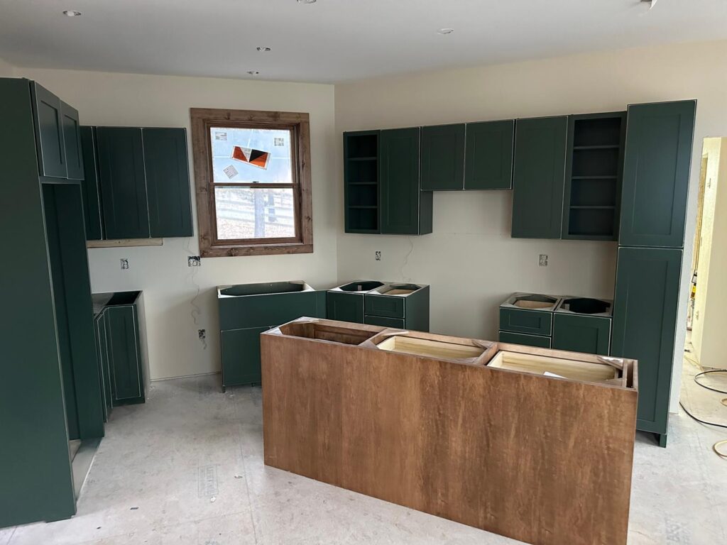 Custom white oak kitchen cabinets with a large marble island, black range hood, and natural stone wall by Max Craft.
