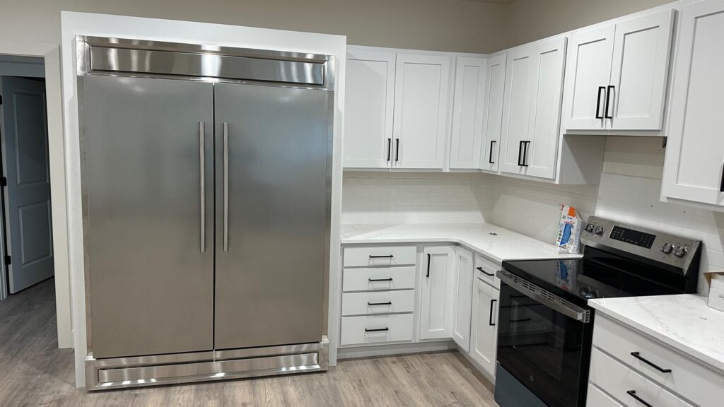 Custom white kitchen cabinetry with built-in refrigerator surround by Max Craft.