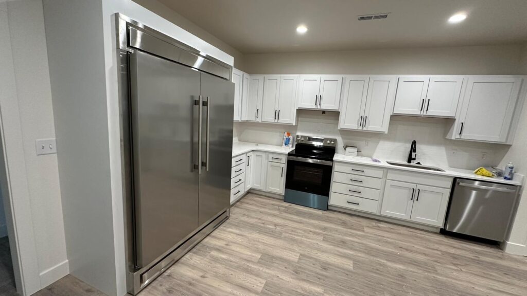 Bespoke white Shaker-style kitchen cabinets with stacked storage and crown molding.