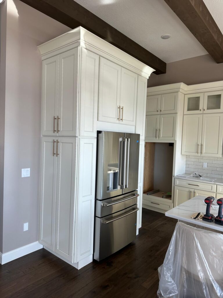 Custom light gray floor-to-ceiling cabinetry with built-in refrigerator surround and stacked pantry storage