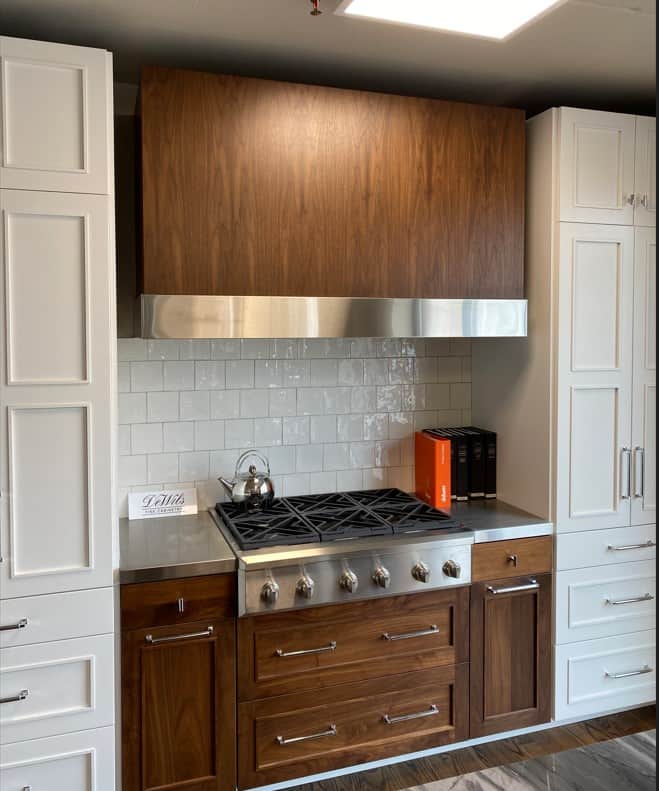 ntegrated Door Panel Hood: The Art of Cohesion – A detailed look at a professional built-in range station, featuring a dark wood range hood and cabinetry that perfectly matches.